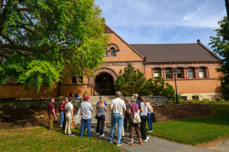 A group of alumni, parents, and friends stand in front of Van Wickle during a walking tour.