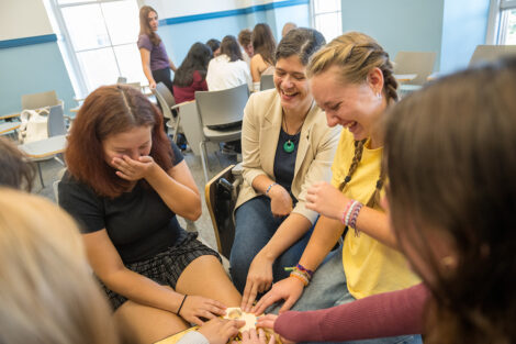 A group of several individuals are laughing as they look at a ouija board.