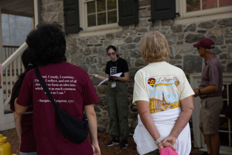 Guests wearing Lafayette College t-shirts stand outside of a historic stone house.