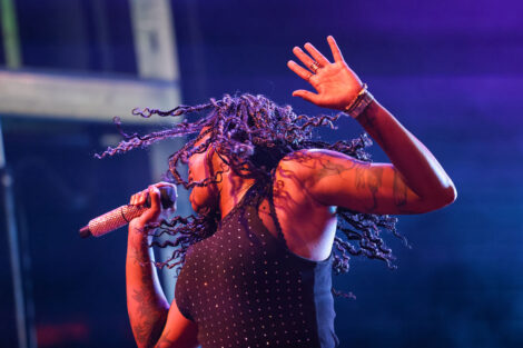 A singer from Fitz and the Tantrums waves her hair in the air, with her hand up.