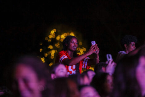 A student holds up their cell phone in the crowd.