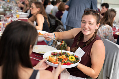 An attendee holds a white plate of food for another attendee.