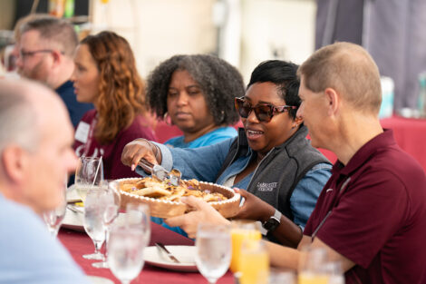 Attendees at the LaFarm to Table breakfast are seated at a table and are passing food.