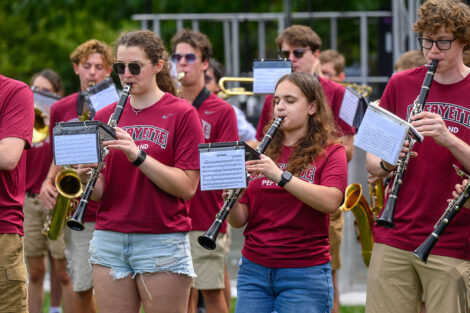 Students play various instruments, including flutes, saxophone, and more, on the Quad.