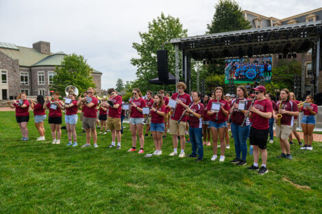 Students play various instruments, including flutes, saxophone, and more, on the Quad.