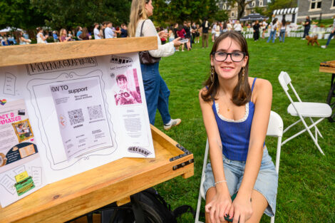 A student sits with her art on display.