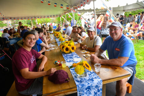 Families sit at long wooden tables with sunflowers as center pieces.