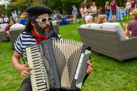 A person plays an accordion dressed up in a french outfit.