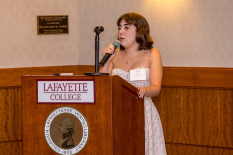A student stands at a podium holding a microphone.