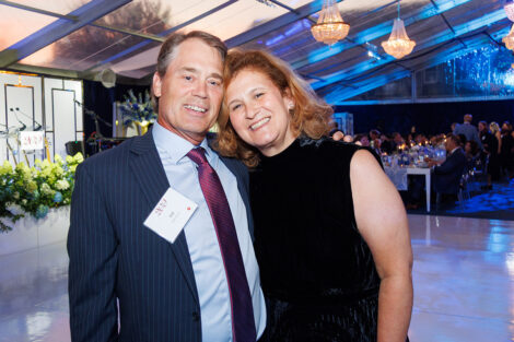 Bill Hurd and President Nicole Hurd smile at the camera. Bill is wearing an pinstripe suit jacket and President Hurd is wearing a black dress.