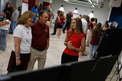 President Nicole Hurd and Bill Hurd listen as a student explains their research.