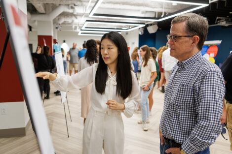 A student points to their research paper while a community member looks on.