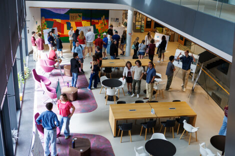 Students stand in the lobby of Rockwell Integrated Sciences Center as community members explore their research.