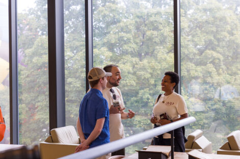 Three alumni talk in the lobby of Skillman Library.