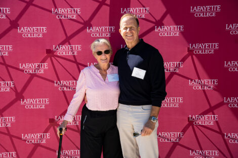 Peggy Lawson (wife of late Coach Bill Lawson) and Evan Deoul '84 stand in front of a Lafayette College sign at the Wallach dedication.