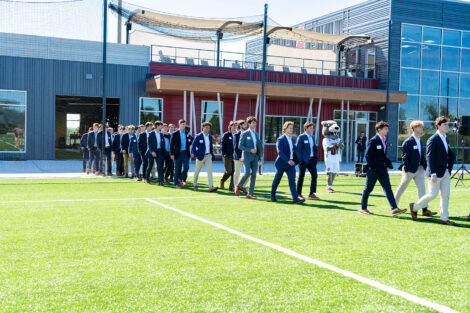 Members of the men's lacrosse team enter onto the new turf field from the Wallach Center.