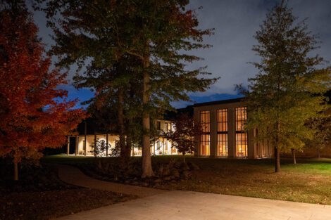 George Washington Presidential Library at night, surrounded by large trees.