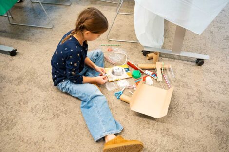 Girl Scout sitting on floor with art supplies and working on a science project for Girl Scout Badge Day