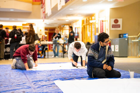 Students decorate a white sheet with blank paint for the Lehigh banners.