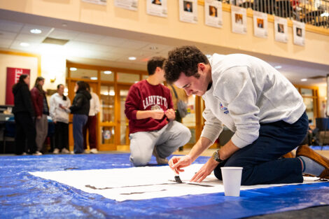Students decorate a white sheet with blank paint for the Lehigh banners.