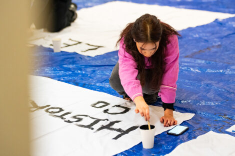 Students decorate a white sheet with blank paint for the Lehigh banners.