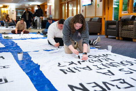 Students decorate a white sheet with blank paint for the Lehigh banners.
