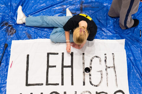 Students decorate a white sheet with blank paint for the Lehigh banners.