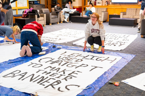 Students decorate a white sheet with blank paint for the Lehigh banners.