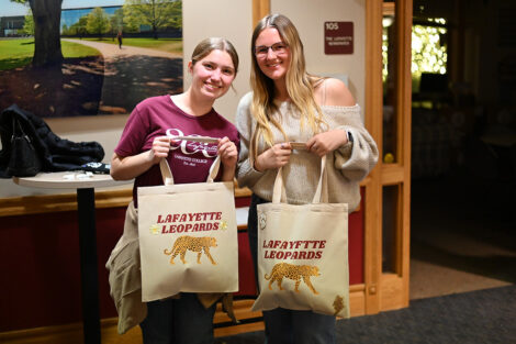 Students hold canvas totes that read 