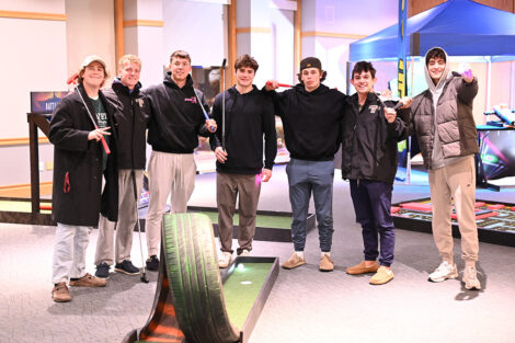 Students play indoor mini golf.