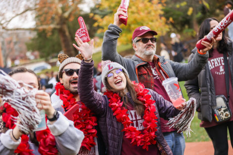 Lafayette College community members cheer, dressed head to toe in leopard and maroon gear.