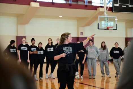 Katie McConnell, head coach for the women’s lacrosse team, directs participants in Kirby Sports Center as student-athletes look on.
