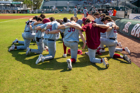 Members of the Lafayette baseball team are in a circle and are on one knee on a baseball field.