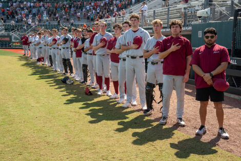 Members of the Lafayette baseball team stand in line with their hats off and their hands on their heart for the 
