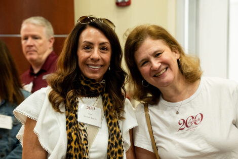 Fran Della Badia and Nicole Hurd are standing next to each other and smiling at the camera. They are wearing white shirts.
