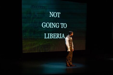 Man on stage in front of projection that says Not Going to Liberia