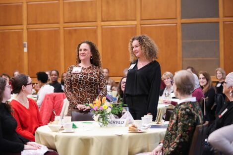 Two attendees stand up at a table among a crowd