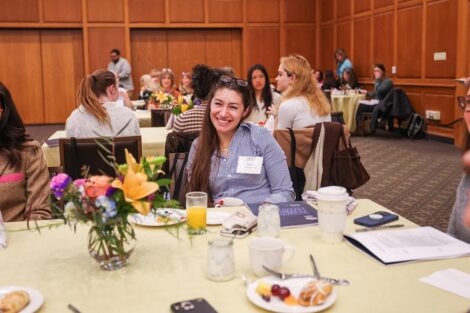 An attendee smiles at a table during breakfast