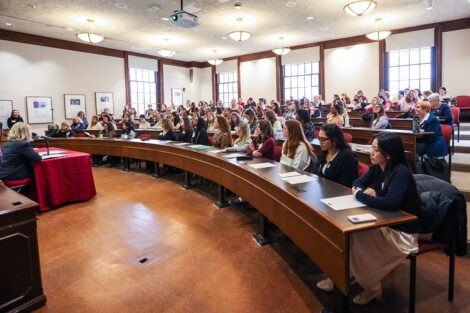 A lecture hall is filled with attendees listening to a Conference presentation