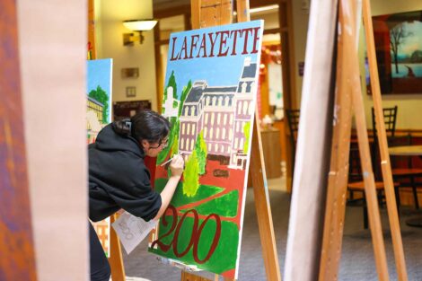 Student painting the Founders' Week mural