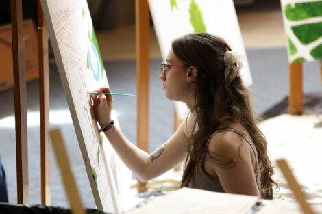 Student painting the Founders' Week mural