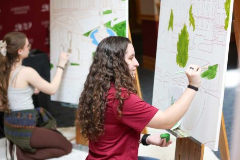 Student painting the Founders' Week mural