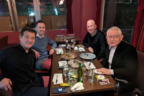Four men sit at a table and smile