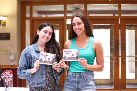 Two students pose with Founders Day postcards