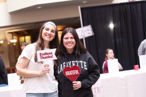 Two people pose with signs that say Endless Thanks and Grateful