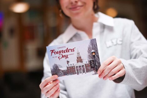 A person holds a Founders Day postcard to camera