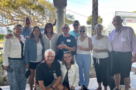 People pose in front of palm trees outside