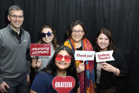 Photobooth shot of a group posing with signs that say grateful
