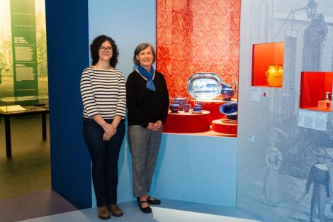 Ramirez Luhrs (left) and Stomber pose in front of cobalt-blue commemorative ceramics loaned by the College.