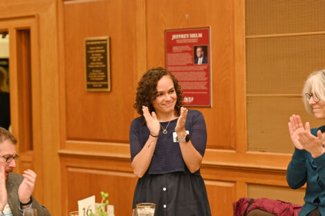 A faculty member stands and claps.